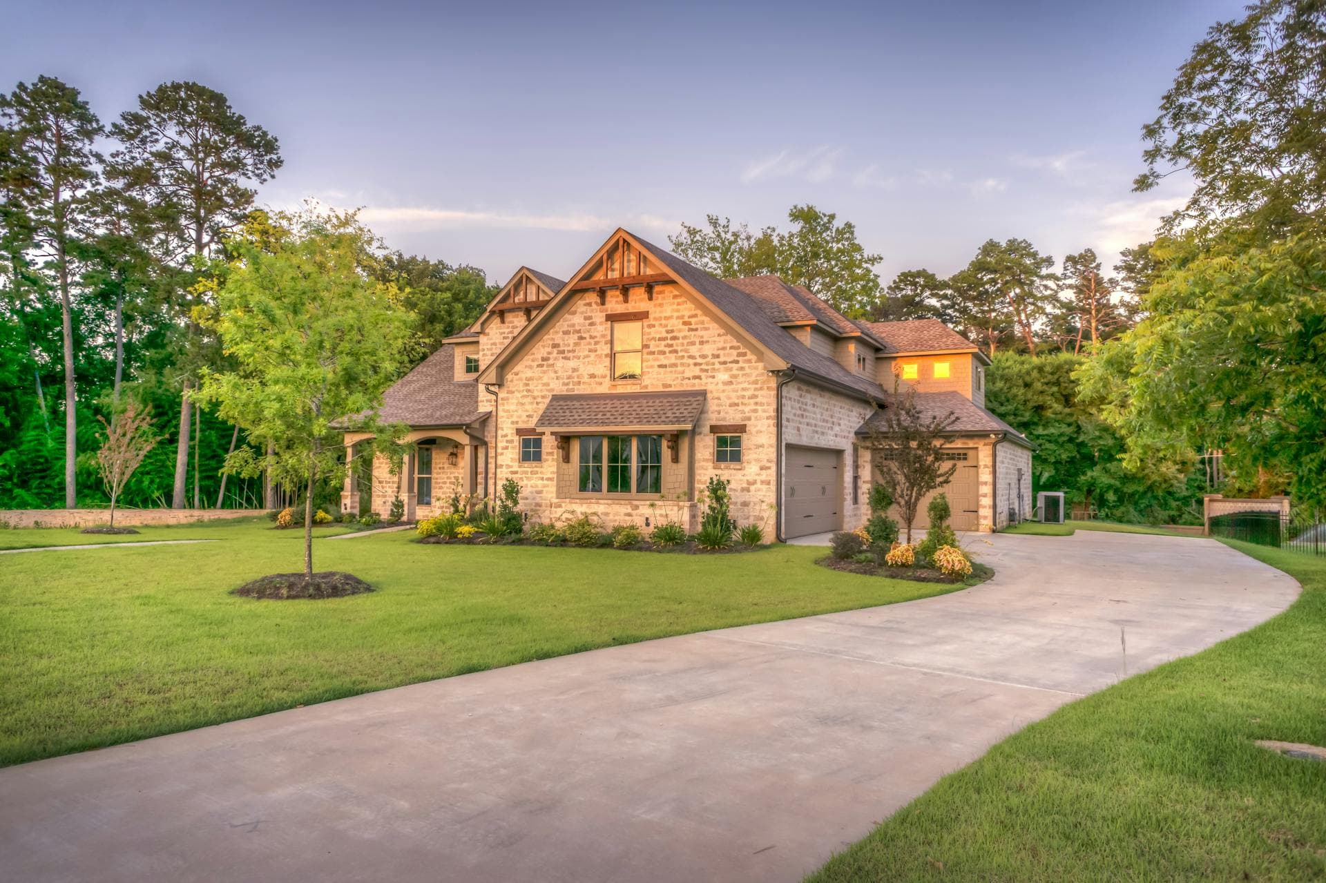 Beautifully landscaped home with green lawn, trees, and clean mulch beds near Central Iowa.